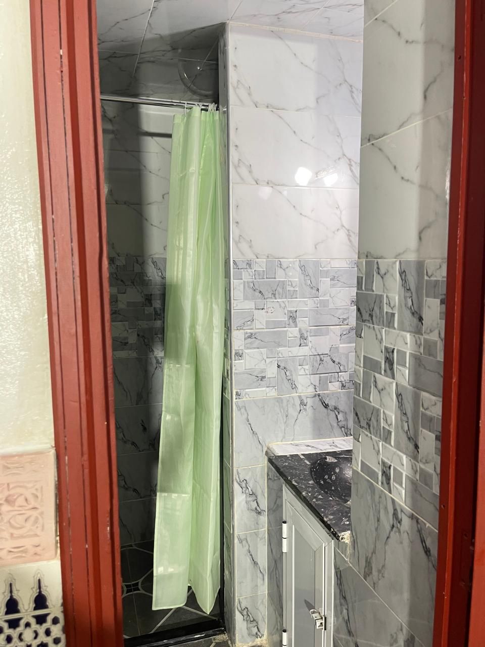A bathroom with a shower, tiled walls, and a countertop.