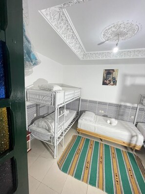Une chambre avec des lits superposés, un tapis à motifs et un plafond orné de décorations complexes.