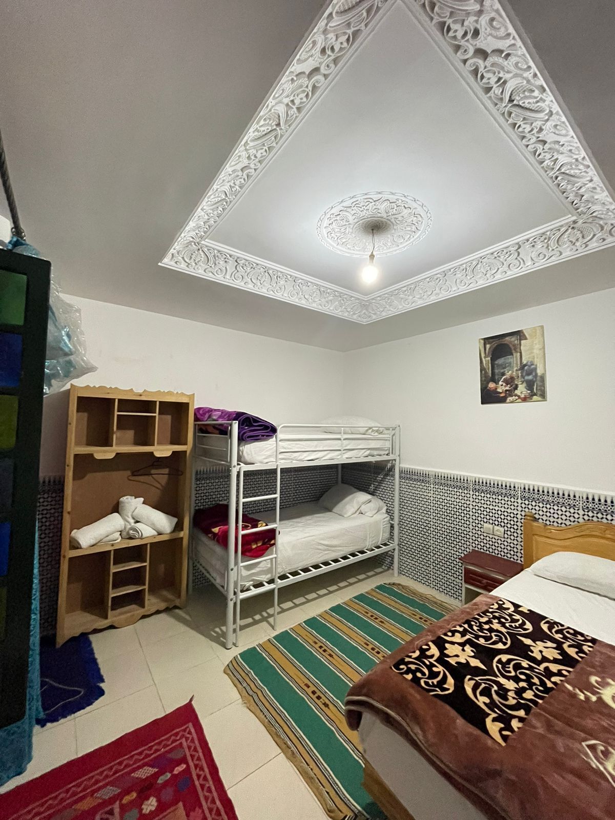 Un dormitorio con literas, un armario, una alfombra estampada y un techo con diseños elaborados.