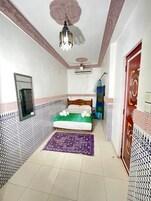 Quarto com cama, espelho, ventilador de teto e paredes estampadas.