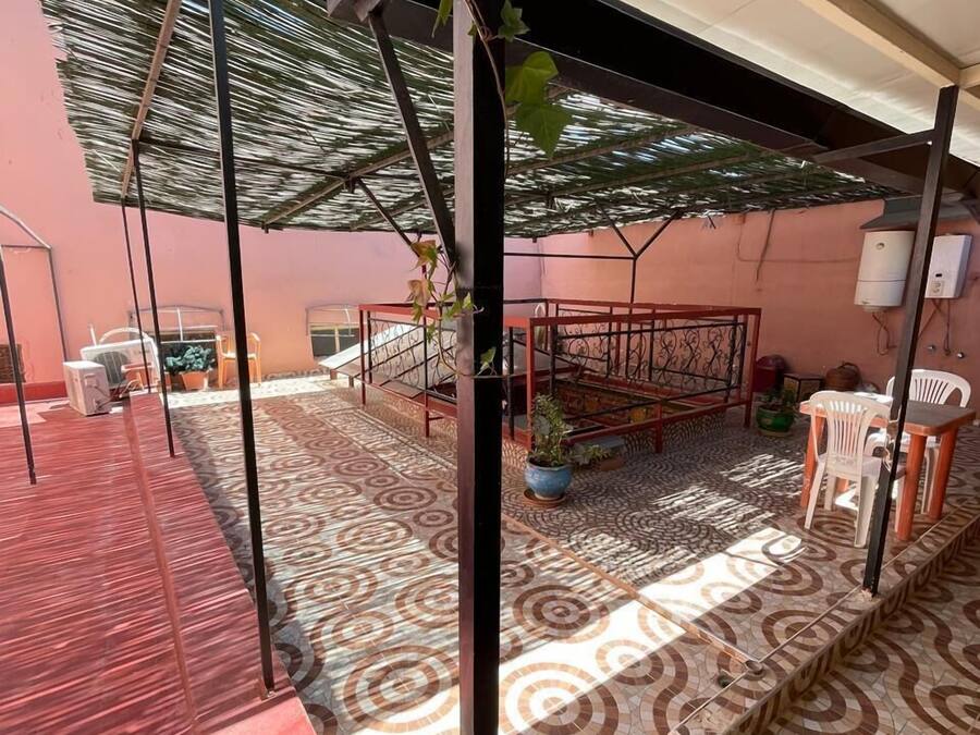 Un espacio al aire libre techado con piso estampado, barandilla metálica y plantas en macetas.