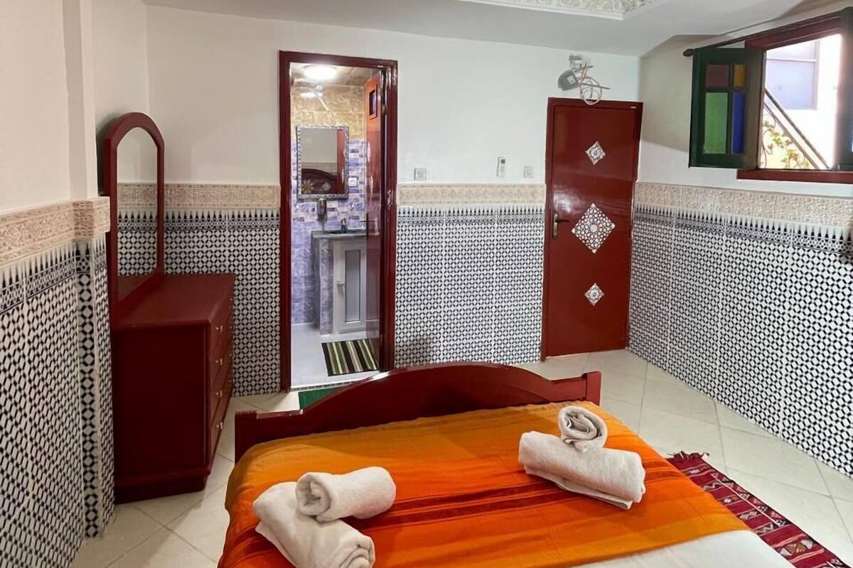 A hotel room with a bed, a dresser, a mirror, and a door leading to a bathroom.