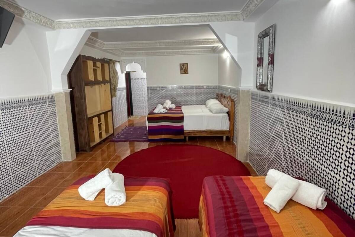 A hotel room with two beds, a red carpet, and a wooden wardrobe.