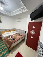 Quarto com cama, porta vermelha e paredes estampadas.
