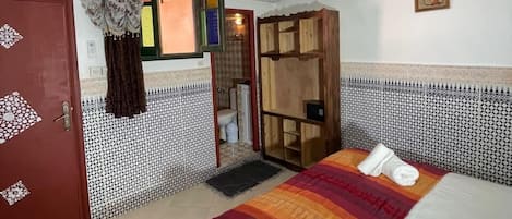 Una habitación de hotel con cama, armario, baño y puerta.