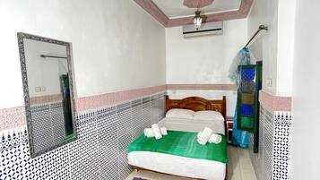 Un dormitorio con cama, espejo, ventilador de techo y paredes con diseño.