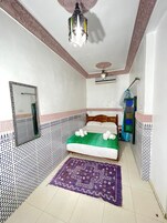 Un dormitorio con cama, espejo, ventilador de techo y paredes con diseño.
