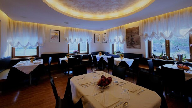 Un ristorante con tavoli rotondi, tovaglie bianche e una luce soffusa al soffitto.