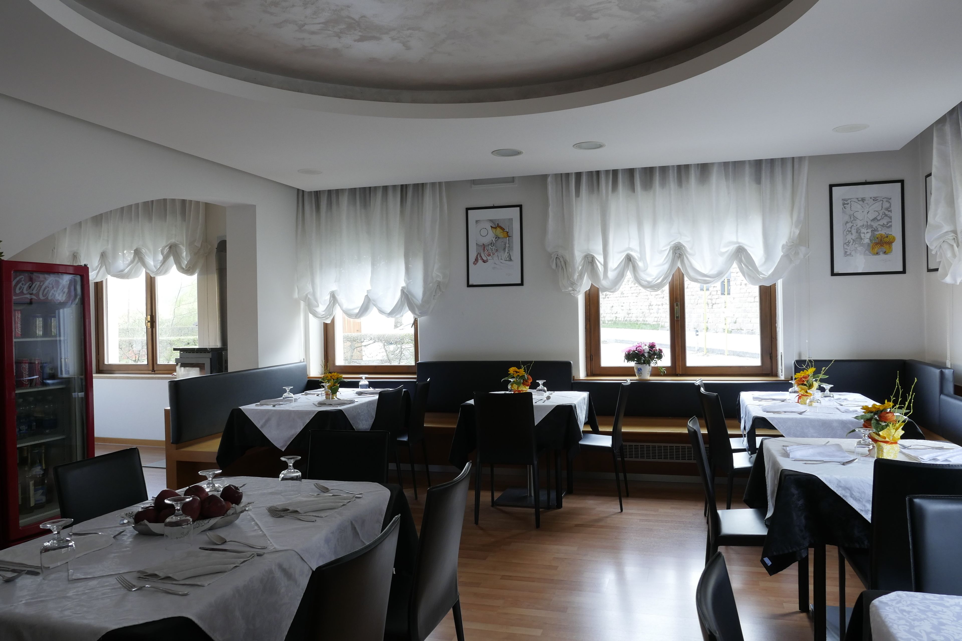 Comedor con mesas dispuestas, sillas y una estantería.