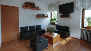 Un soggiorno moderno con pavimento in legno, divani neri, un tavolino, una televisione e una pianta in vaso.