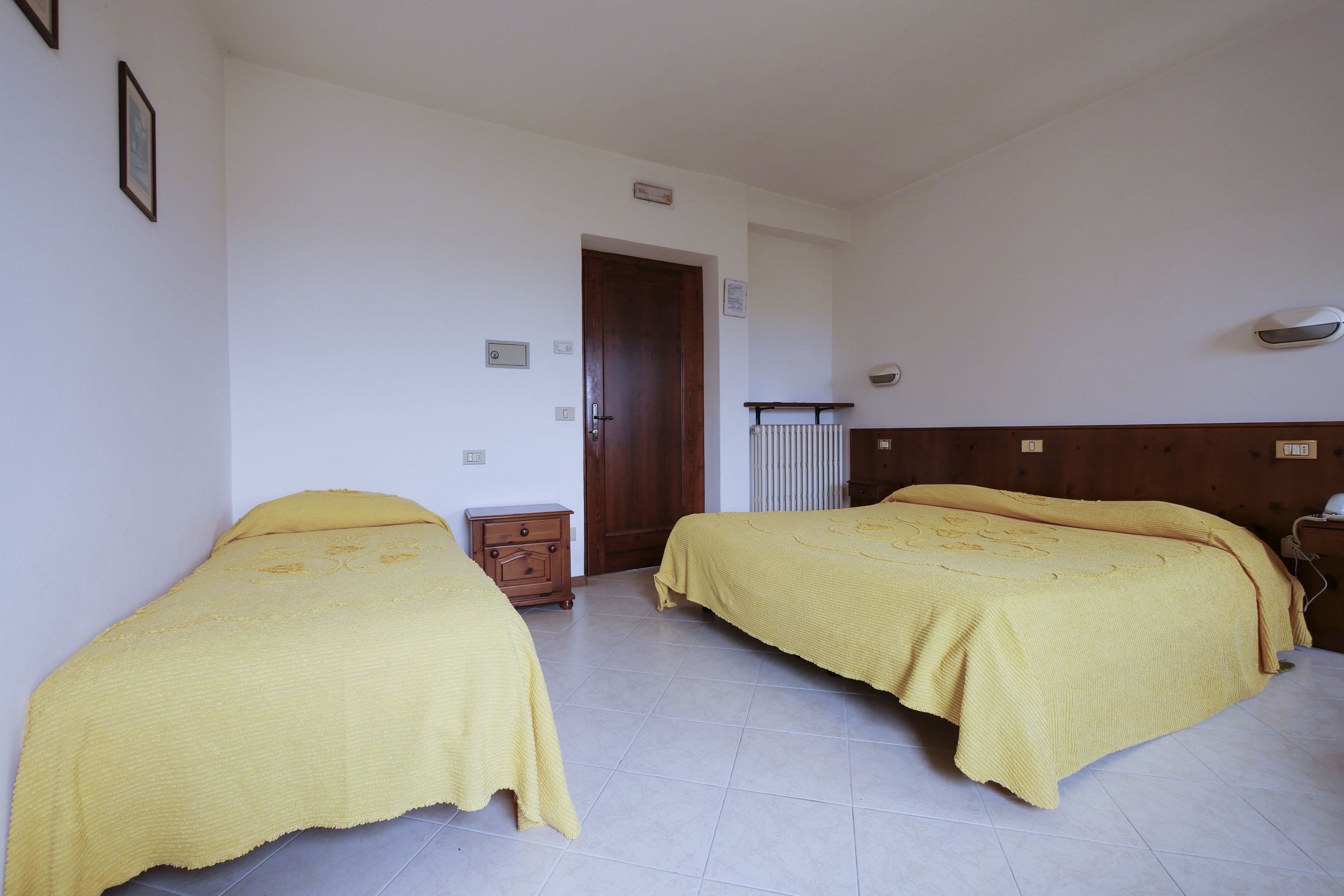 A bedroom with two beds, a wooden wardrobe, and a radiator.