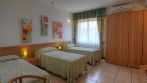 Habitació d'hotel amb dos llits individuals, un armari de fusta i una nit{0}era amb una làmpada.