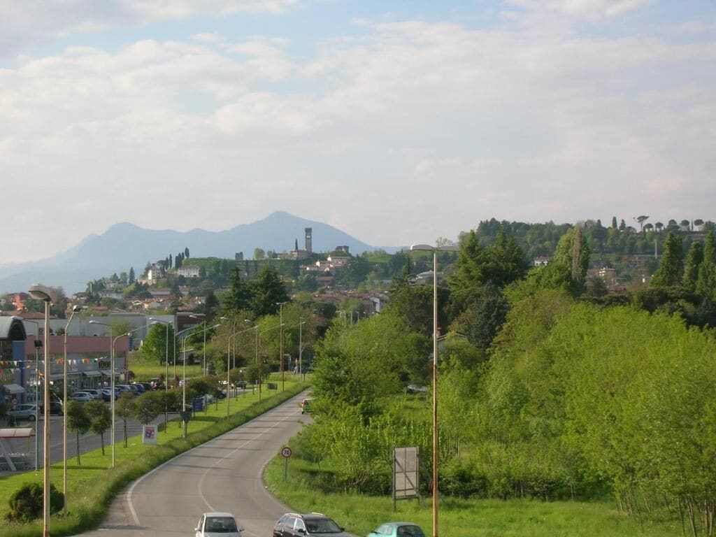 A road curving through a town with buildings and greenery.