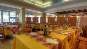Un restaurant amb taules grogues, cadires de fusta i un pilar de pedra.