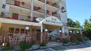 Edifici de diverses plantes amb un cartell que diu "Bar Ristorante" i balcons amb plantes.