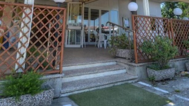 Un edifici amb un rètol que diu "BAR RISTORANTE" i balcons amb baranes.
