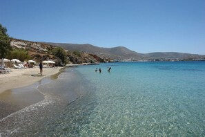 Una spiaggia con acqua cristallina, ombrelloni e persone.