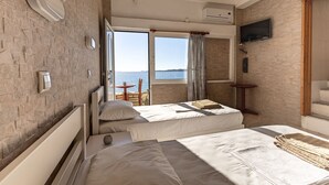 Ett hotellrum med två sängar, en TV och utsikt över havet.