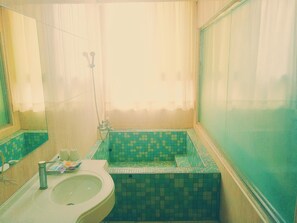A bathroom with a sink, a mirror, a shower, and a tiled wall. - Jade Spring Hot Spring Hotel (Jiaoxi)