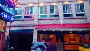 Un hotel de varios pisos con un toldo rojo y varias ventanas iluminadas.