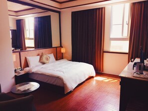A hotel room with a bed, a desk, a chair, a lamp, and a window with curtains. - Jade Spring Hot Spring Hotel (Jiaoxi)