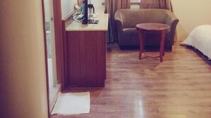 Una habitación de hotel con un escritorio de madera, una silla, un sofá y una cama.