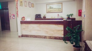 Un área de recepción con mostrador de mármol, certificados enmarcados en la pared y un cuadro encima.