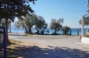 Une propriété située sur la côte, avec une allée en gravier, un bâtiment blanc doté d’un toit en verre et une vue sur la mer.