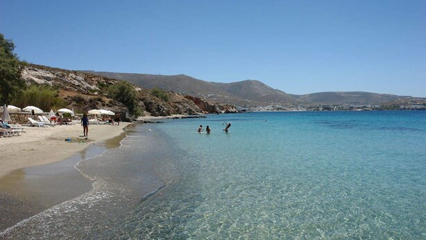 A beach with clear water, umbrellas, and people. - Krios Beach Camping (Paros)