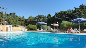 A swimming pool with clear blue water, surrounded by lounge chairs and umbrellas. - Krios Beach Camping (Paros)