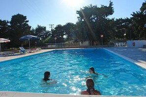 Une piscine à l’eau d’un bleu limpide, entourée de chaises longues et de parasols.