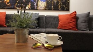 A living room with a coffee table, a newspaper, a cup of coffee, a pair of sunglasses, and a potted plant.
