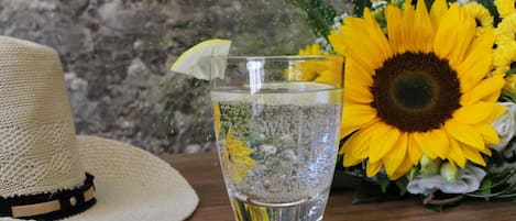 A straw hat, a glass of water with a lemon slice, and a bouquet of sunflowers.
