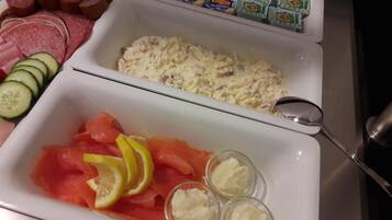 Un buffet proposant une variété de plats, notamment du saumon, du fromage frais et des tranches de concombre.