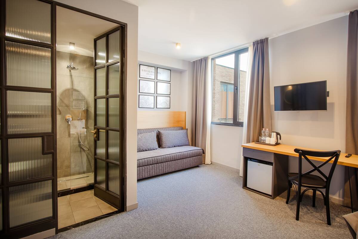 standard quadruple room (with sofa) | living area | flat-screen tv