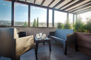 Ein moderner Außenbereich mit Sitzgelegenheiten, darunter ein Tisch für Tee, eine Couch und eine Bank, mit Blick auf eine malerische Landschaft.