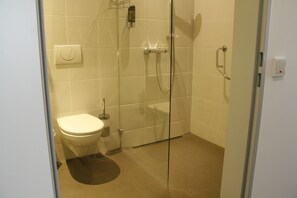 A modern bathroom with a toilet, a glass shower enclosure, and a hand dryer. - Hotel Dornberg (Vechelde)