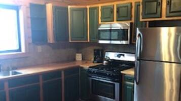 A kitchen with wooden cabinets, a stove, a microwave, and a refrigerator.