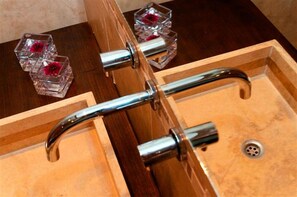 A bathroom with a wooden vanity, a sink, and two glass containers with red flowers. - Casas del Mar (Villa Gesell)