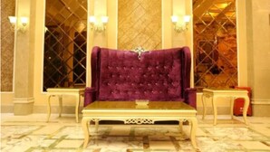 A plush purple sofa with a decorative backrest, positioned in front of a patterned wall with a window. - Karen Hotel (Guangzhou)