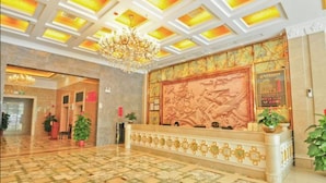A lobby with a reception desk, a chandelier, and a patterned wall. - Karen Hotel (Guangzhou)