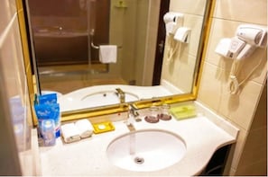 A bathroom with a sink, mirror, and hairdryer. - Karen Hotel (Guangzhou)