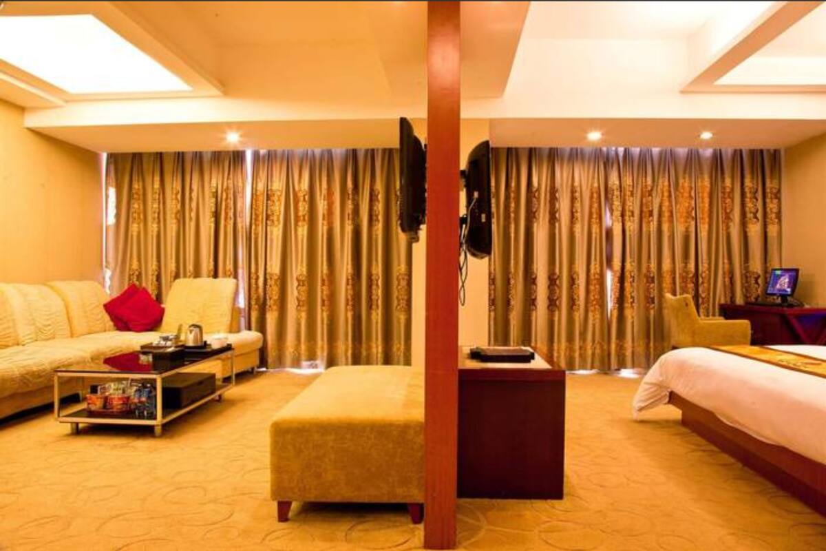A hotel room with a sofa, a bed, a coffee table, and a TV.
