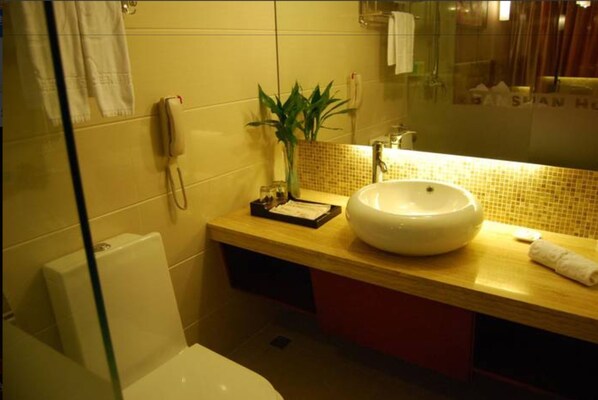 A bathroom with a large white sink, a mirror, a telephone, and a plant. - Eastern Banshan Hotel (Shenzhen)