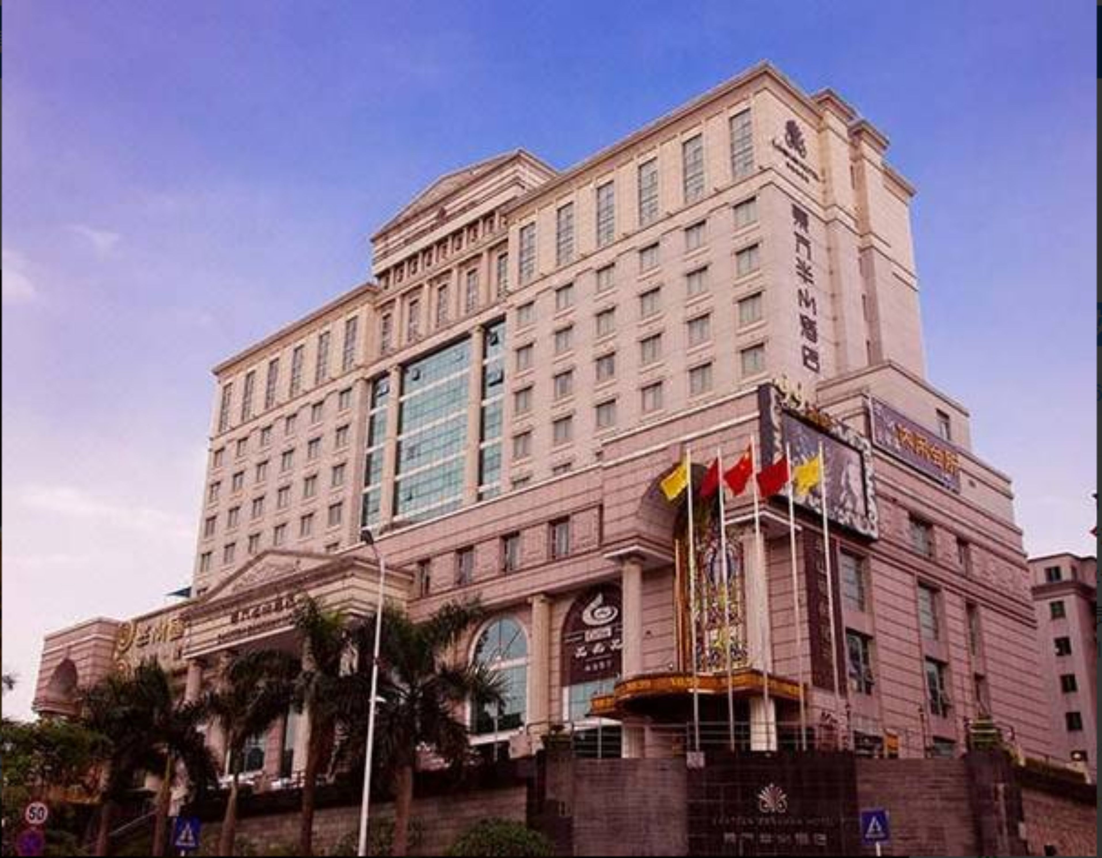 A large, multi-story hotel with a classical architectural style, featuring a prominent entrance with flags and a large glass facade.