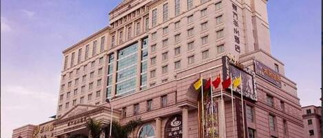 A large, multi-story hotel with a classical architectural style, featuring a prominent entrance with flags and a large glass facade.