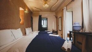 Ein Hotelzimmer mit einem großen Bett, einem Schreibtisch mit Lampe und Blick ins Freie.
