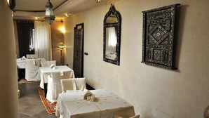 Ein Hotelgang mit gedeckten Tischen, einem Spiegel und dekorativen Wandverkleidungen.