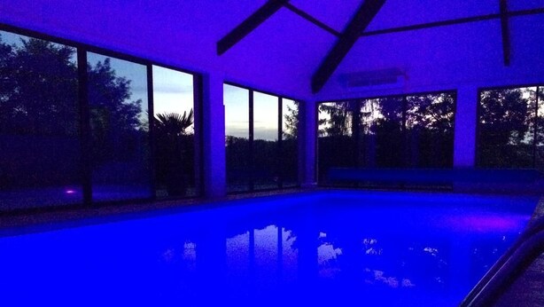 A swimming pool with large windows and a view of trees. - La Conciergerie du Manoir (Saint-Léger-sur-Dheune)