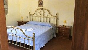 A bed with a metal frame, two bedside tables, and a wall-mounted picture. - Agriturismo Piano di Andrea (Perito)
